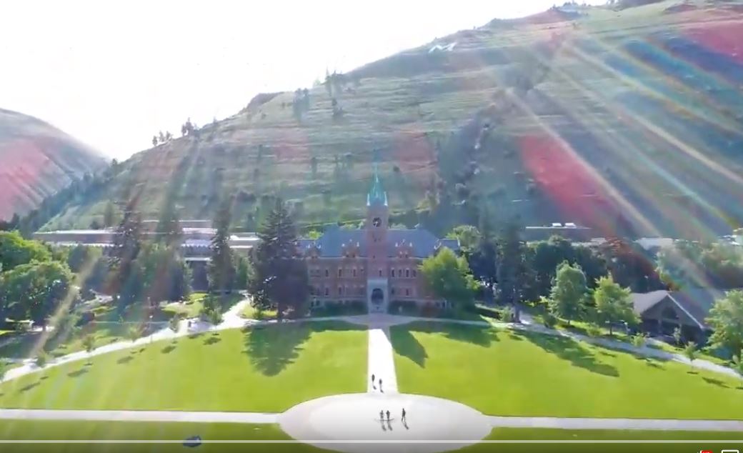 Screenshot from UM drone flyover video of UM main hall with mountain behind